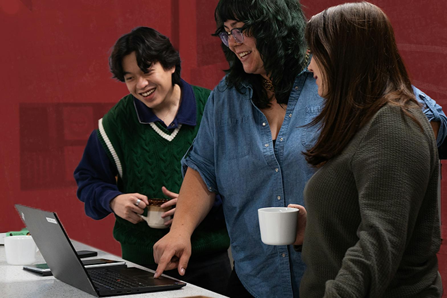 Staff at Narratives huddle around a computer smiling and conversing