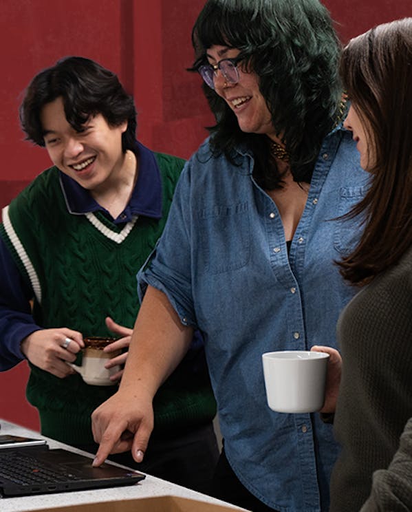 Staff at Narratives huddle around a computer smiling and conversing