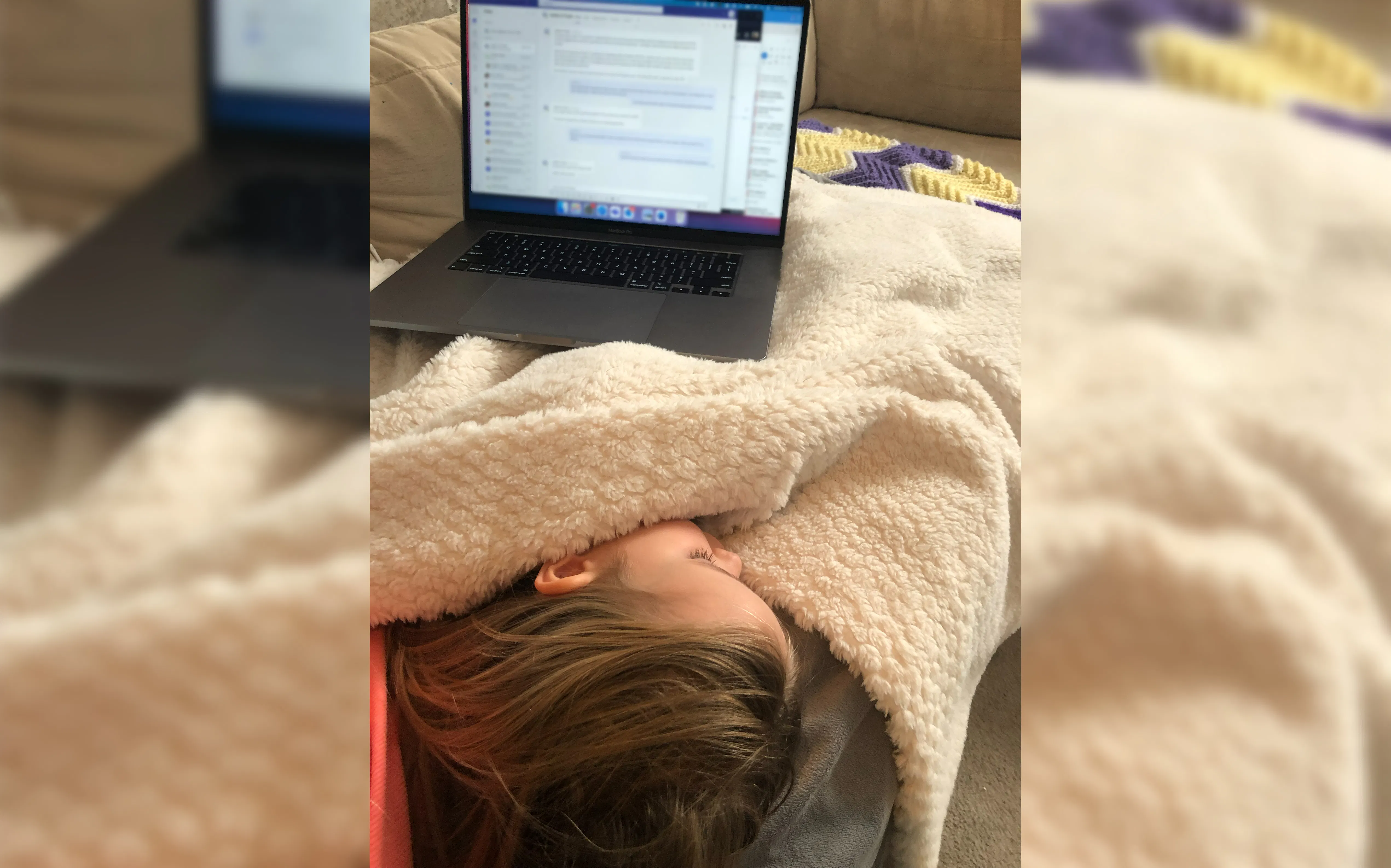 Carly's child sleeping in her lap while her work computer sits near her