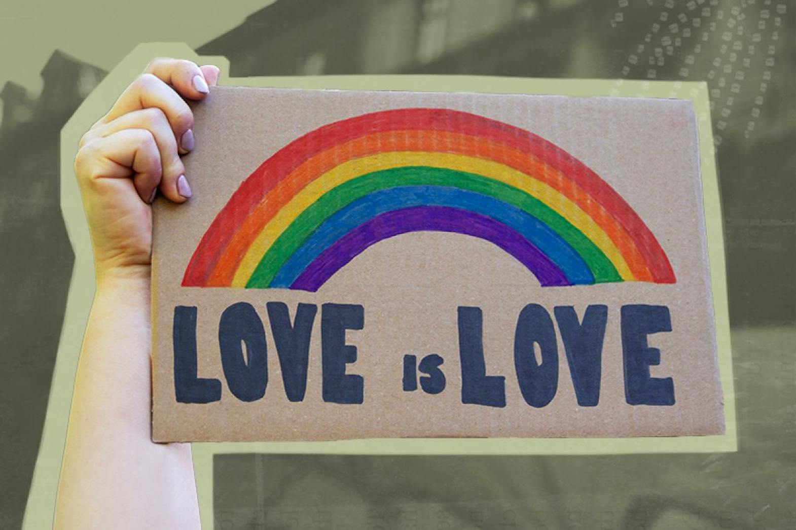 Hand holding up cardboard sign that has a hand drawn rainbow and says Love is Love