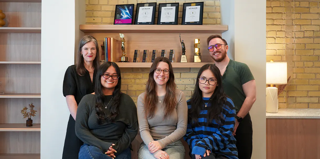 The Expression and Connection team seated in front of a bookcase displaying their awards.