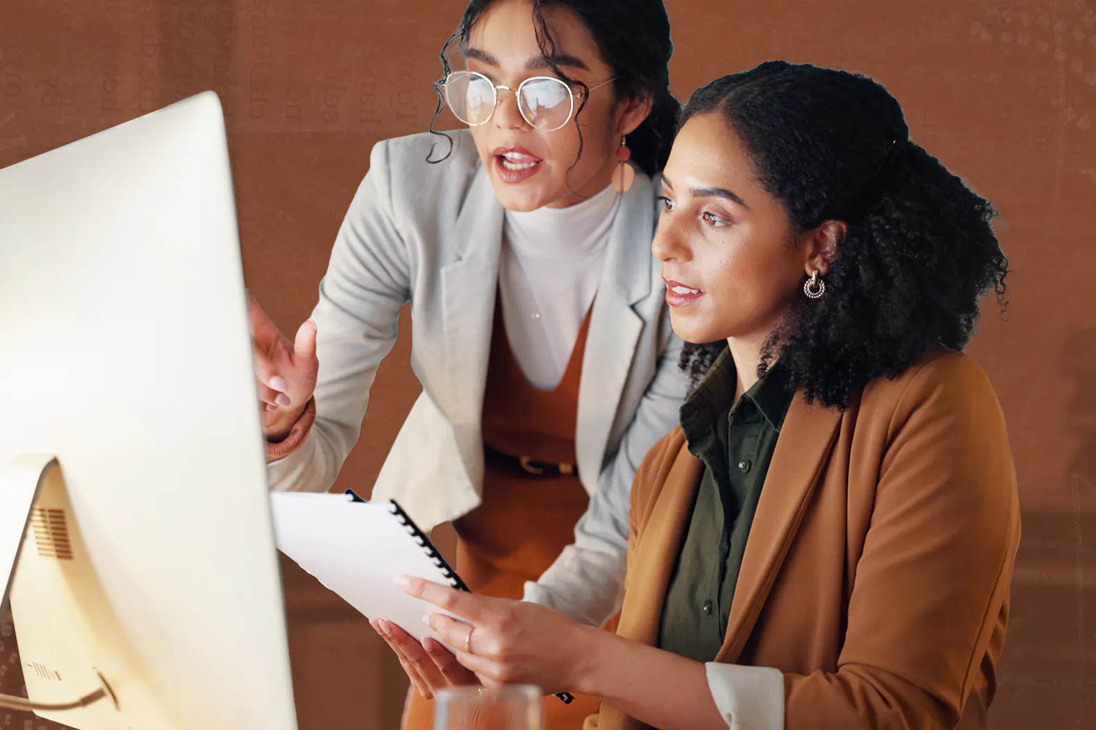 Two women look a ta computer in an office setting