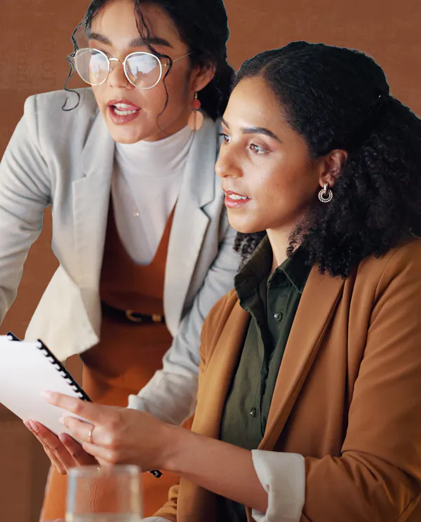 Two women look a ta computer in an office setting