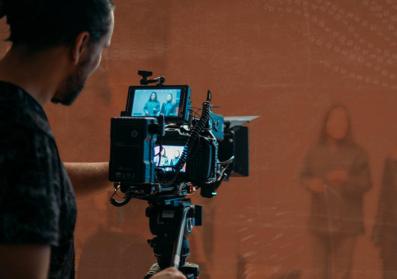 A man works behind a camera filming a video in a studio