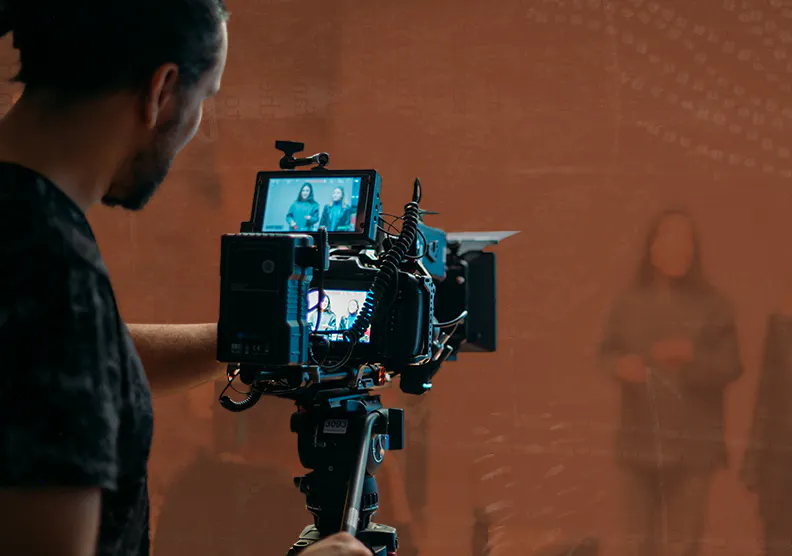 A man works behind a camera filming a video in a studio