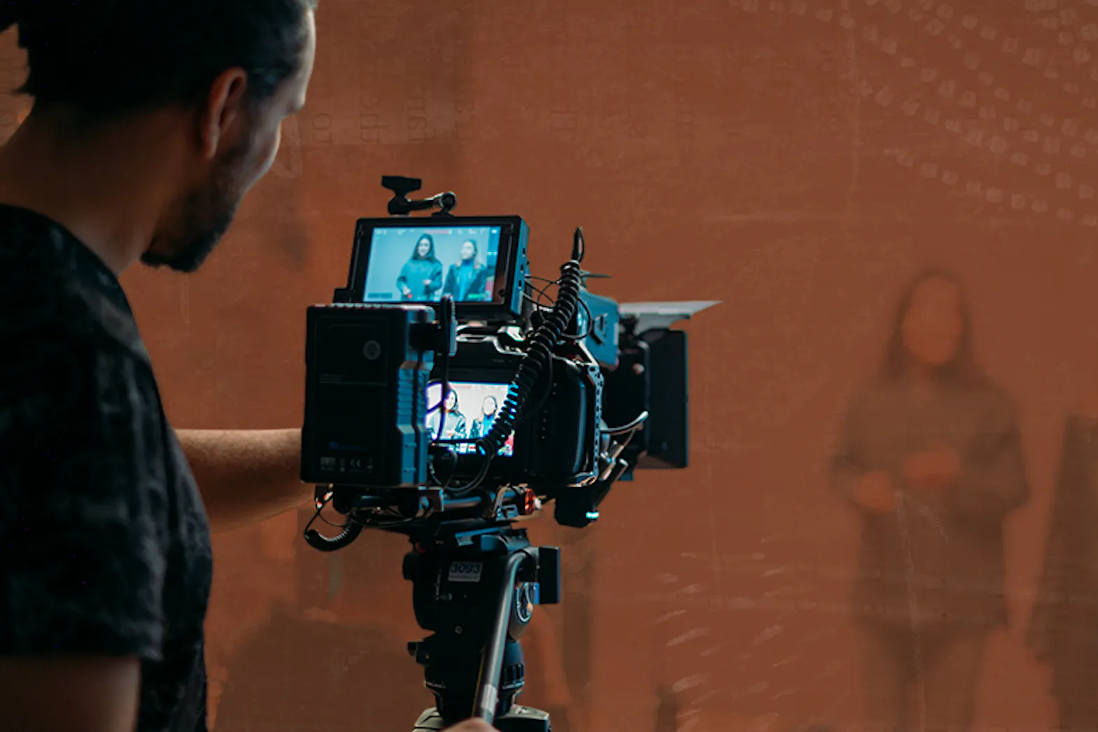 A man works behind a camera filming a video in a studio