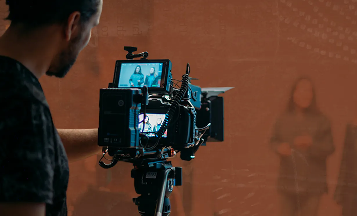 A man works behind a camera filming a video in a studio