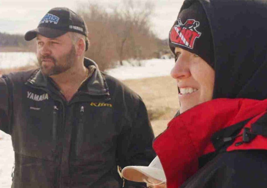 Two individuals in winter gear standing outside looking into the distance