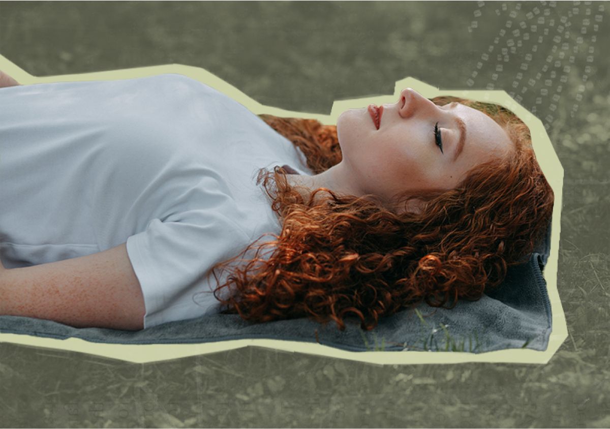 Woman laying in the grass peacefully with her eyes closed
