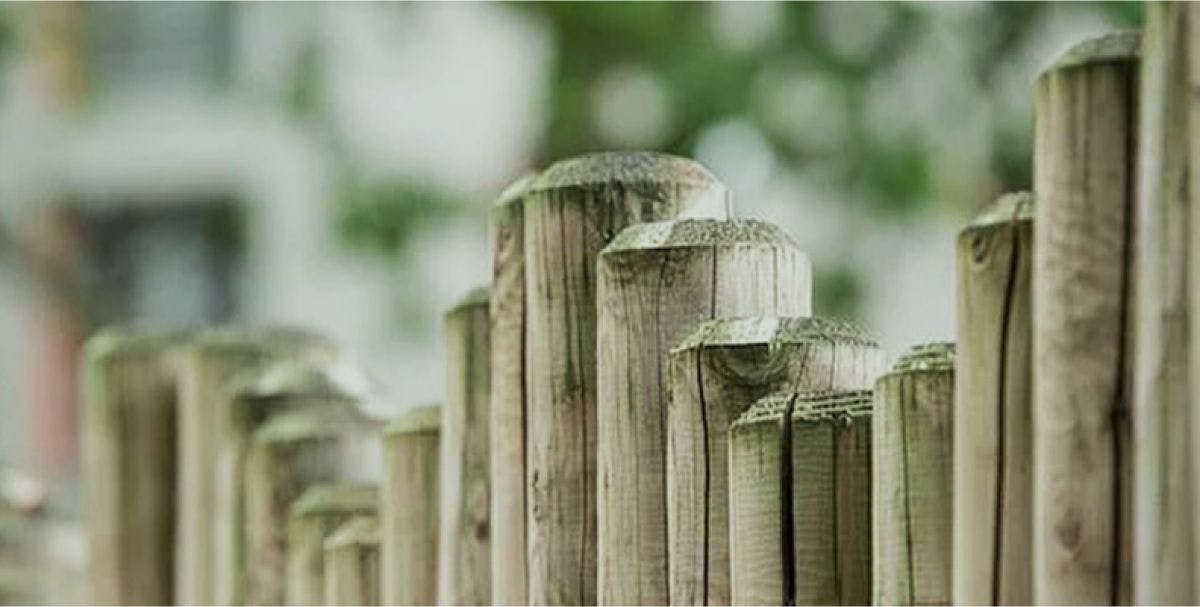 A line of different sized wooden fence posts