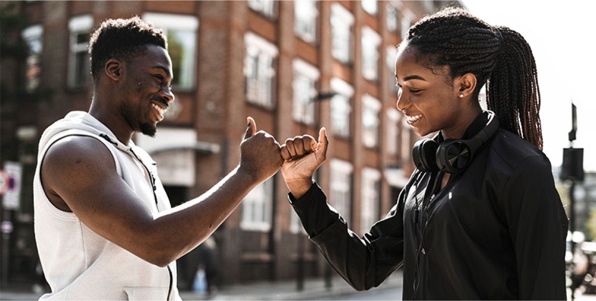 Two people in active wear fist bumping outside