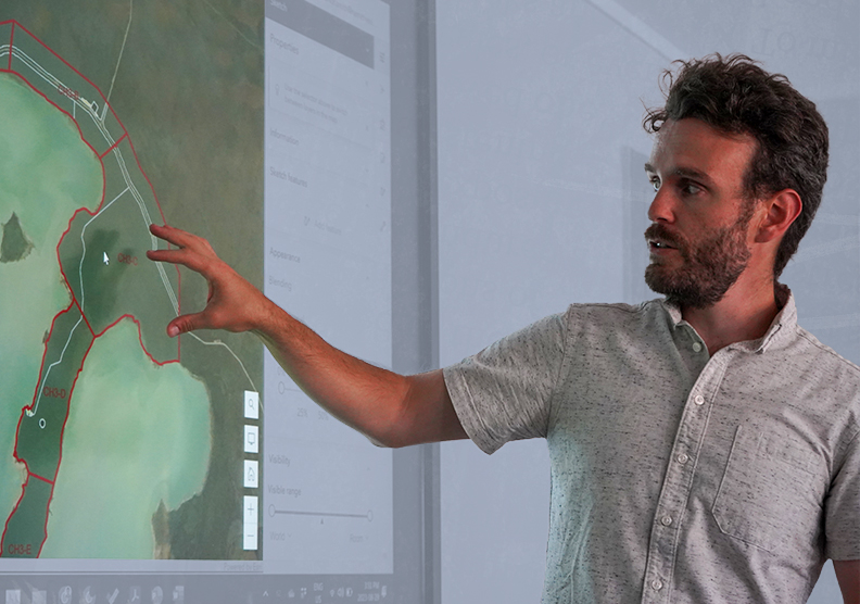 A man points to a map on a computer screen during a digital mapping exercise