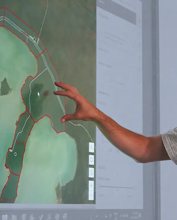 A man points to a map on a computer screen during a digital mapping exercise