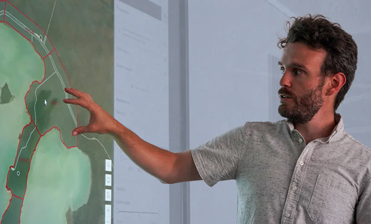 A man points to a map on a computer screen during a digital mapping exercise