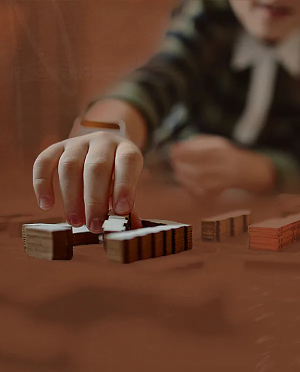 A child playing with wooden building blocks on a coffee table.