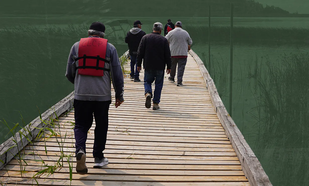 People walking on a dock wearing life jackets. A lake and hills are in the horizon.