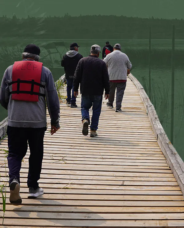 People walking on a dock wearing life jackets. A lake and hills are in the horizon.