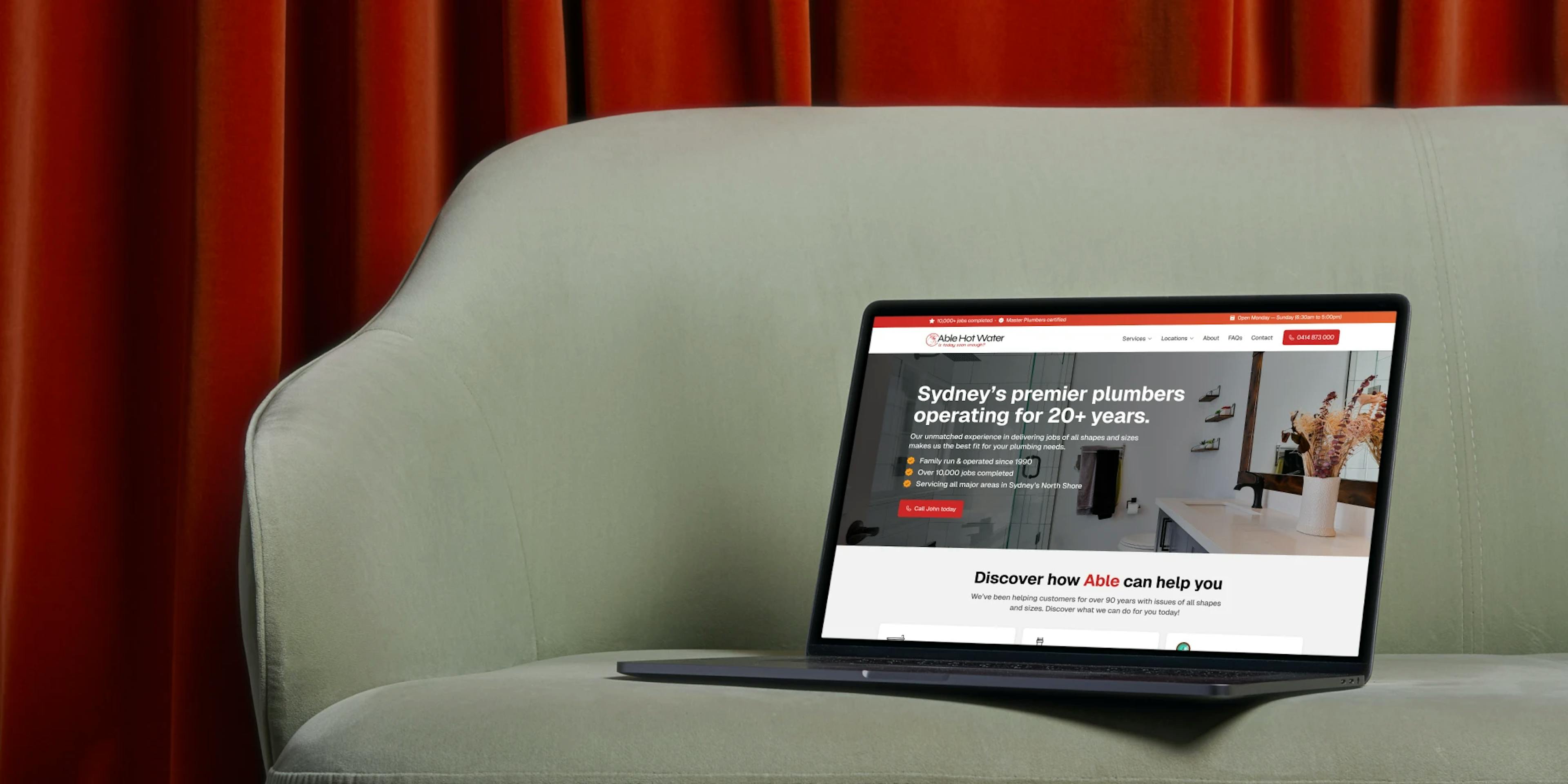 Lounge with a laptop on it and the Able Plumbing website loaded