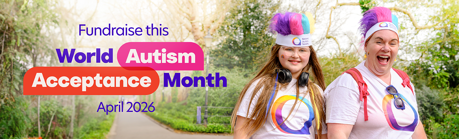 Two people smile for the camera on a path in a park. Both wear matching t-shirts and colourful, fluffy headbands. Text overlay reads, 'Fundraise this World Autism Acceptance Month April 2026
