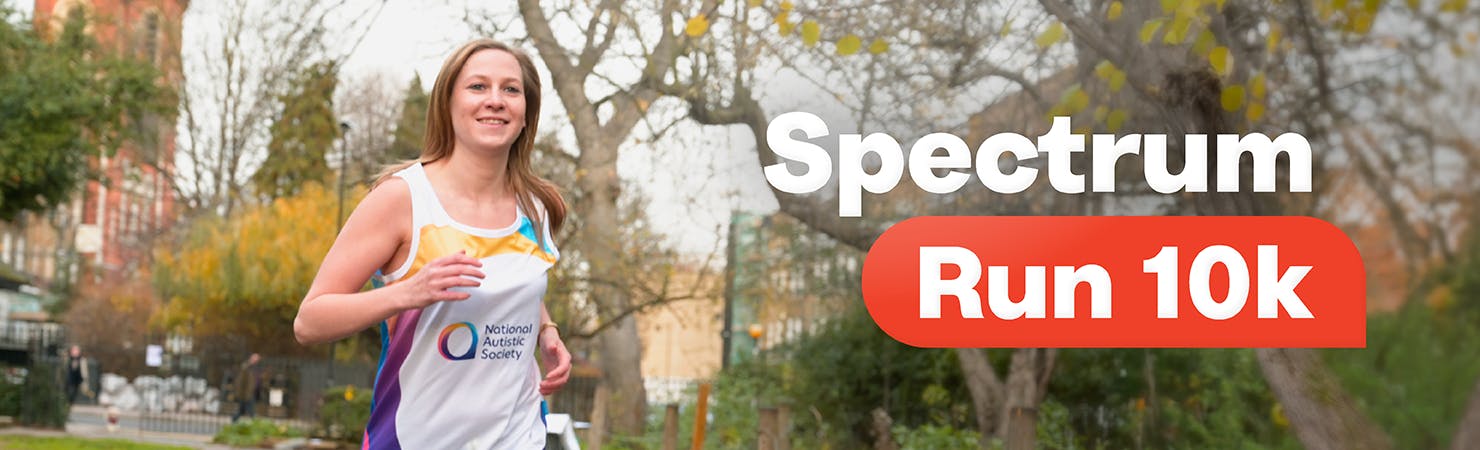 A person runs along a path in a park, smiling at the camera. They are wearing a 'National Autistic Society' running vest. Text overlay reads, 'Spectrum Run 10k'