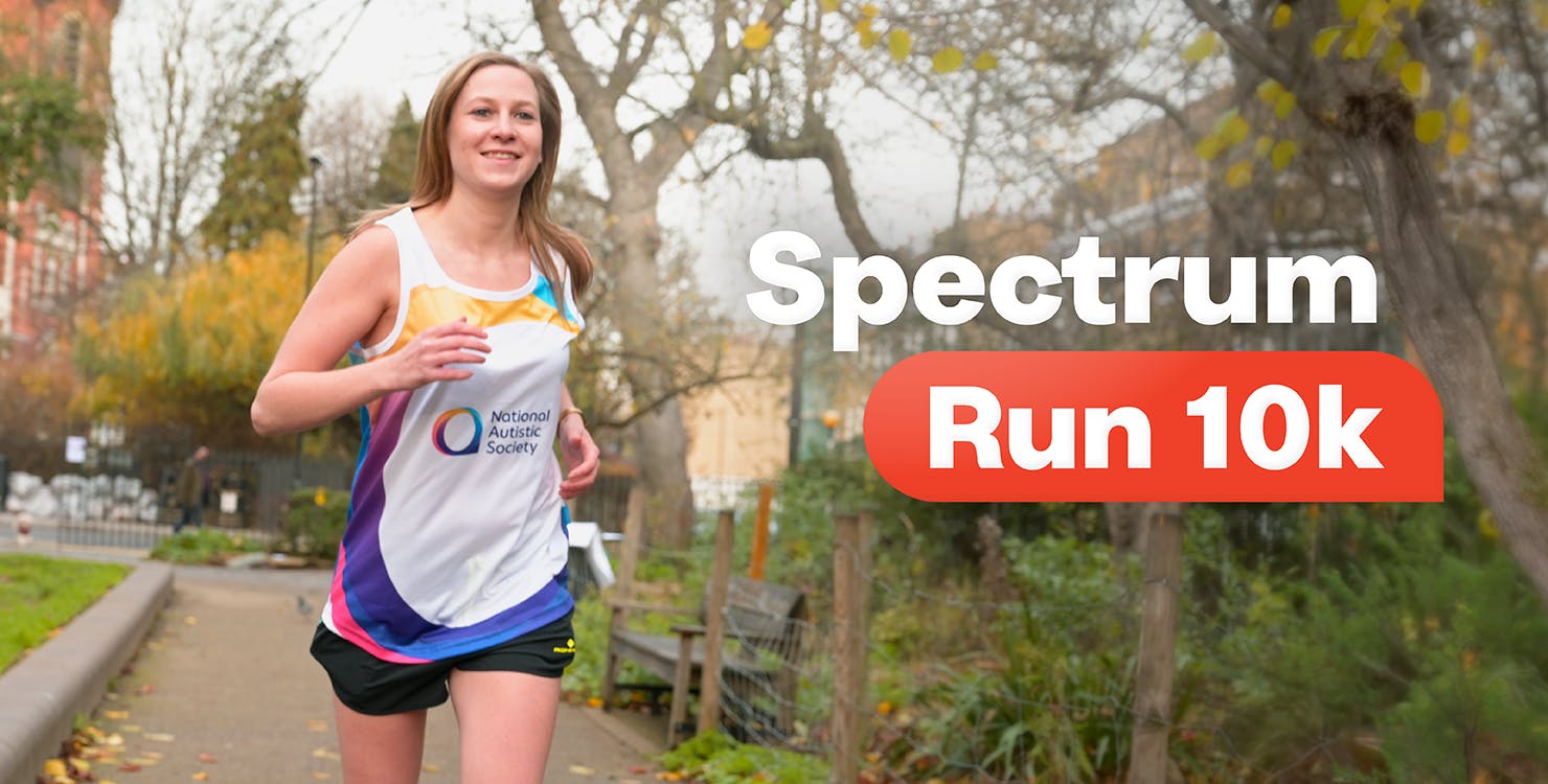 A person runs along a path in a park, smiling at the camera. They are wearing a 'National Autistic Society' running vest. Text overlay reads, 'Spectrum Run 10k'