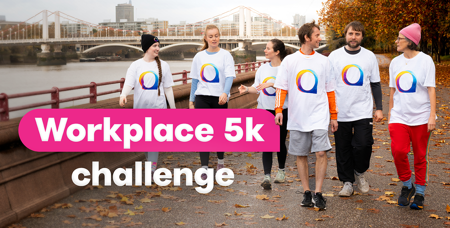 A group of adults wearing National Autistic Society T-shirts walk together along a riverside path lined with autumn leaves. A bridge and city buildings appear in the background. Large text on the image reads 'Workplace 5k challenge'.