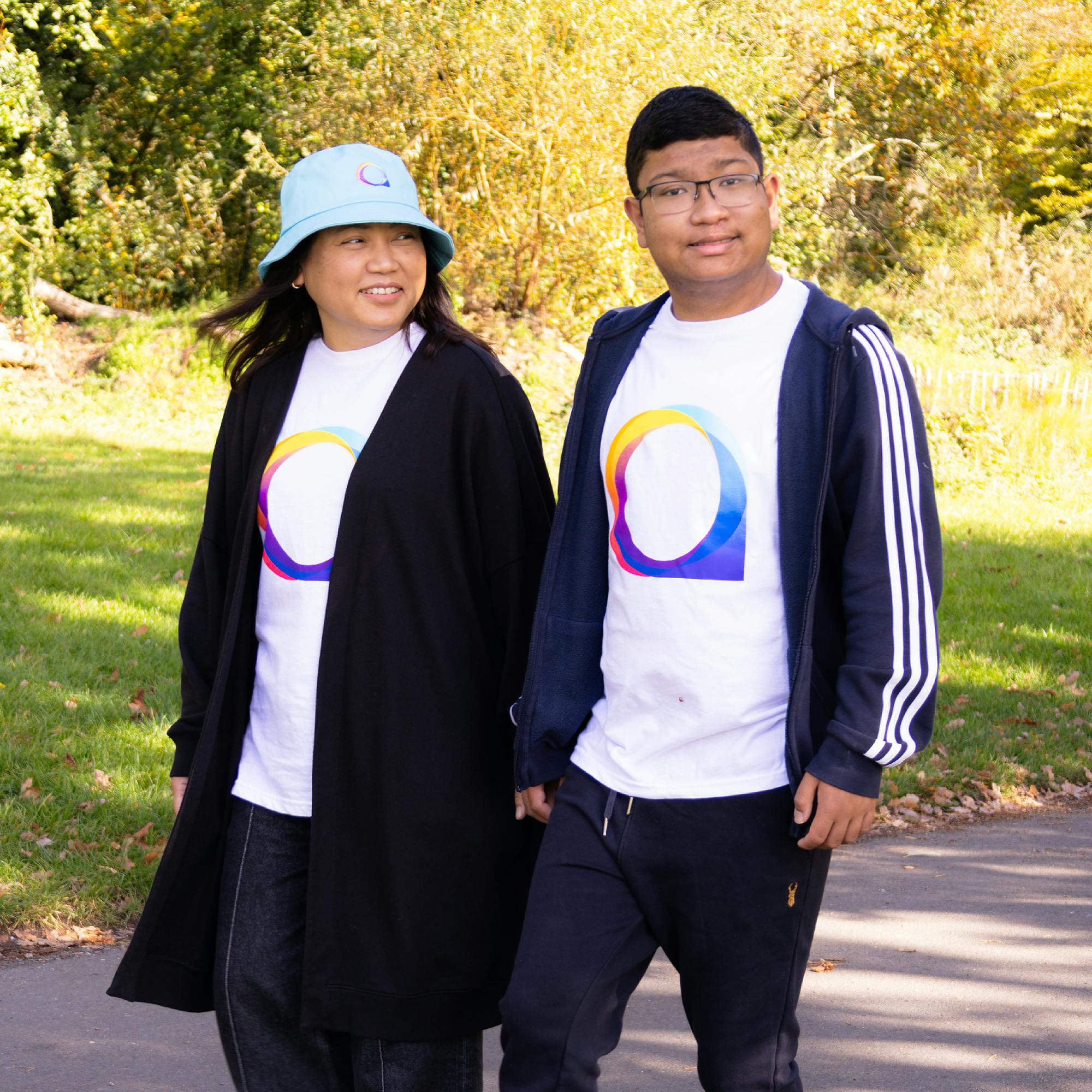 A mother and her adult son together outdoors at an autism awareness event, wearing white T-shirts with the National Autistic Society logo in blue, purple, and orange.