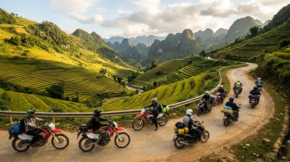 Motorbike riders on the Ha Giang Loop with terraced rice paddies cascading down hillsides below