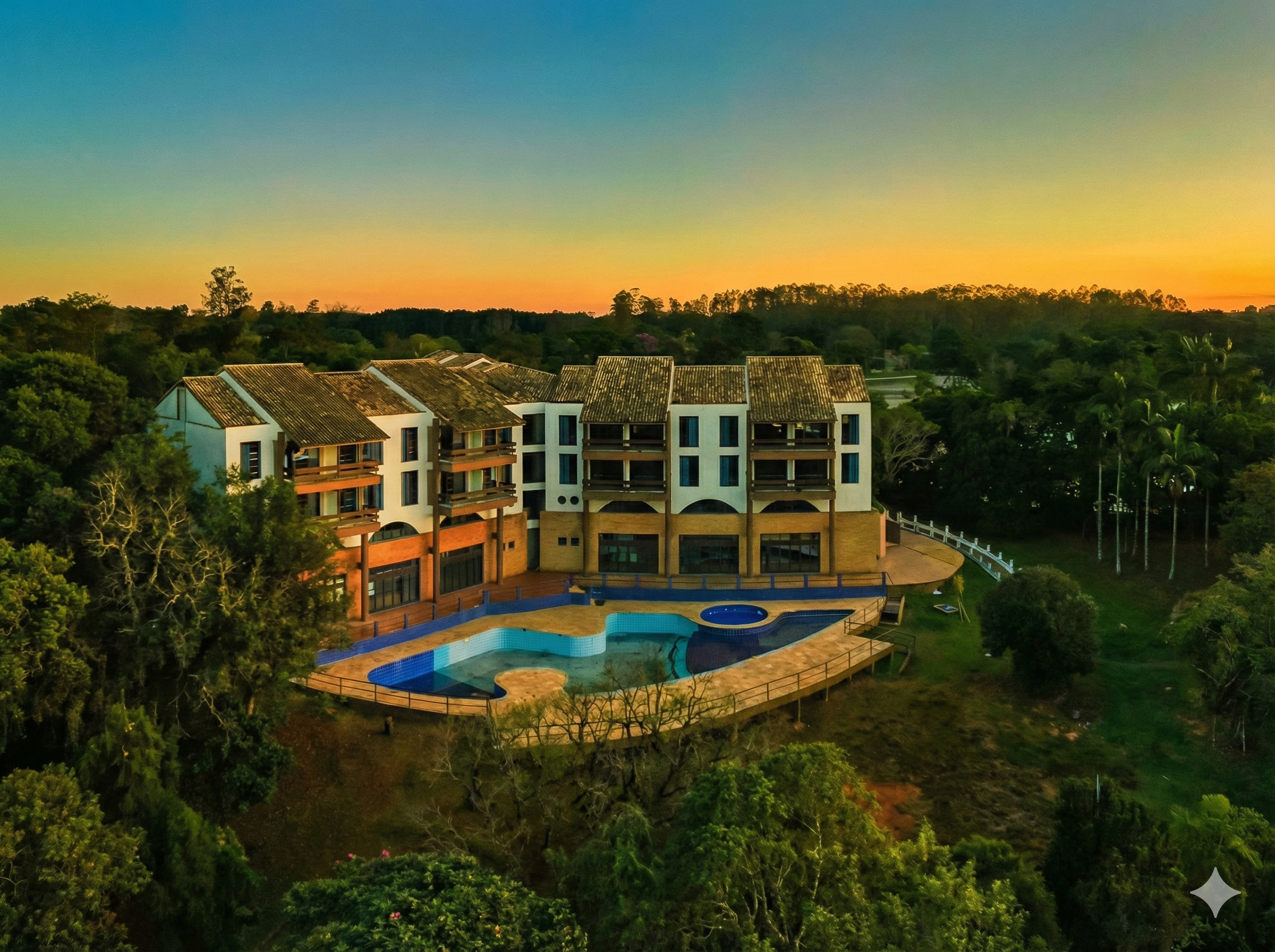 Resort com piscina grande em meio à natureza com pôr do so ao fundo