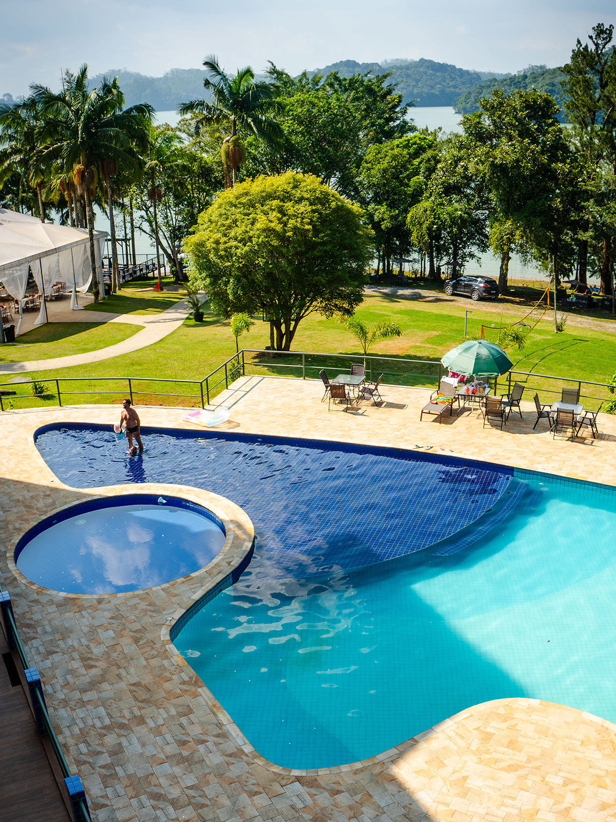 foto aerea de uma piscina de um resort com vegetação ao fundo