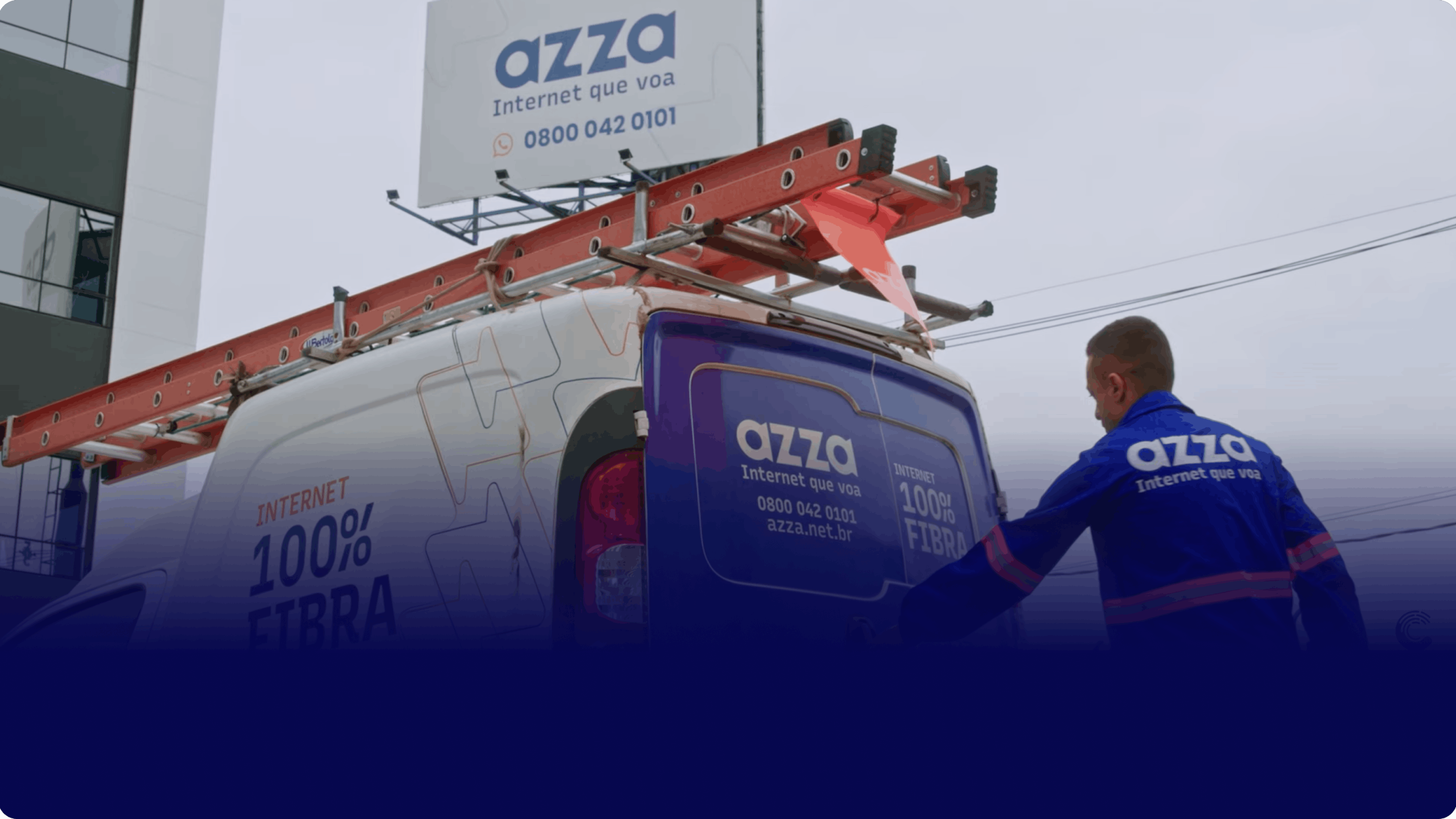 Homem vestindo uma roupa azul com o logo da Azza Telecom atrás de um veículo que também possui o logo da empresa.