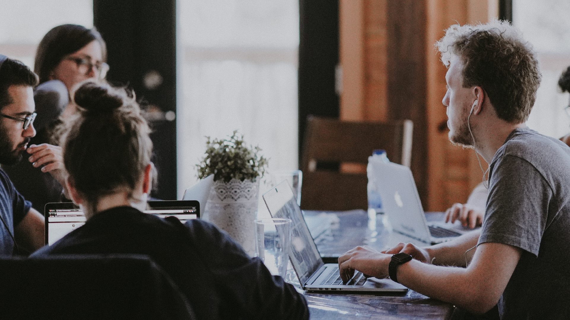 people sitting around a table with their laptops.
