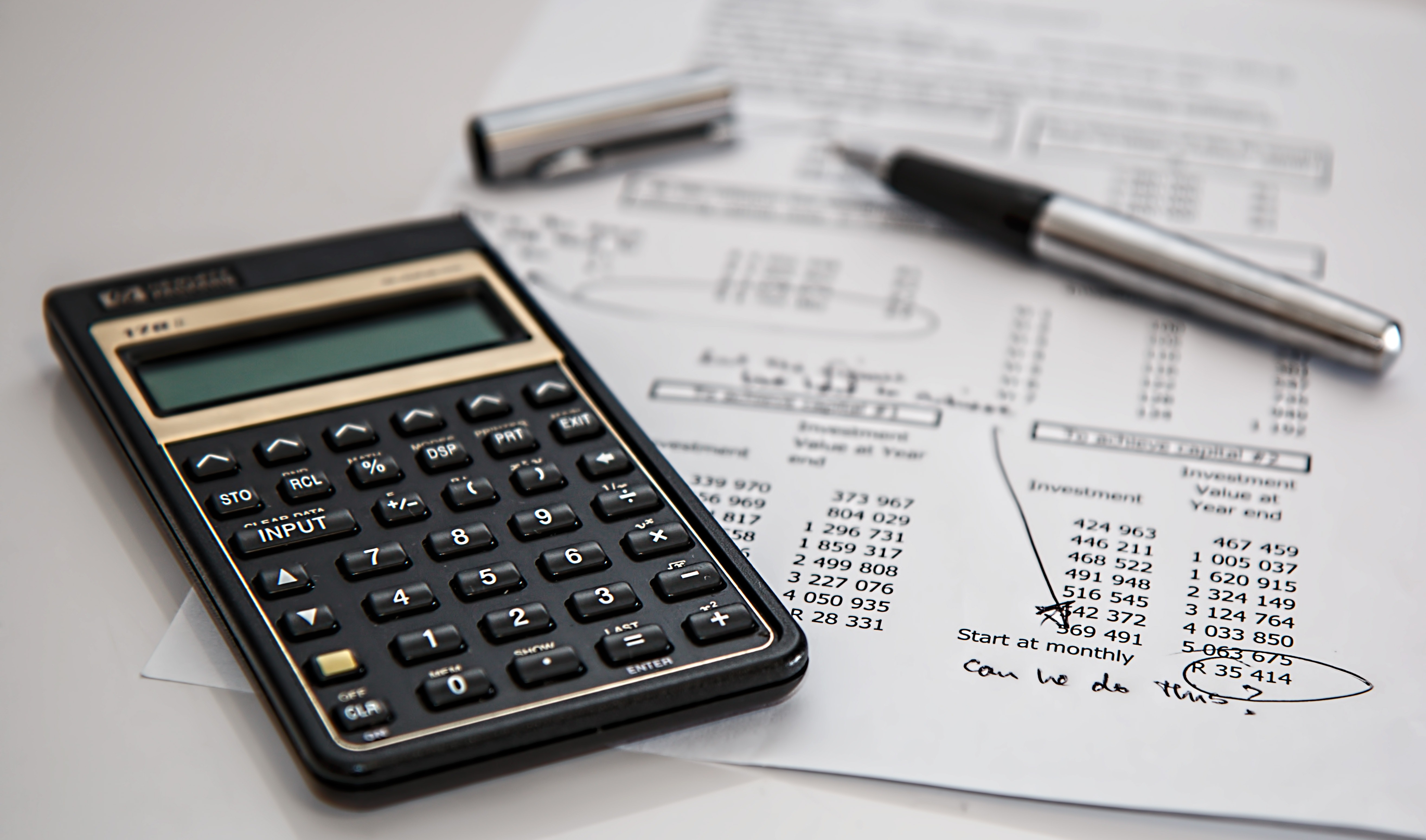 a photo of a calculator and a pen lying on top of a sheet of paper with numbers. The numbers are circled and it says, "can we do this?"