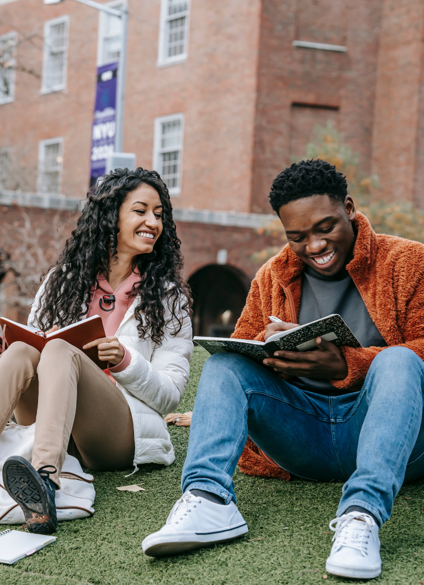 Two students studying outside smiling