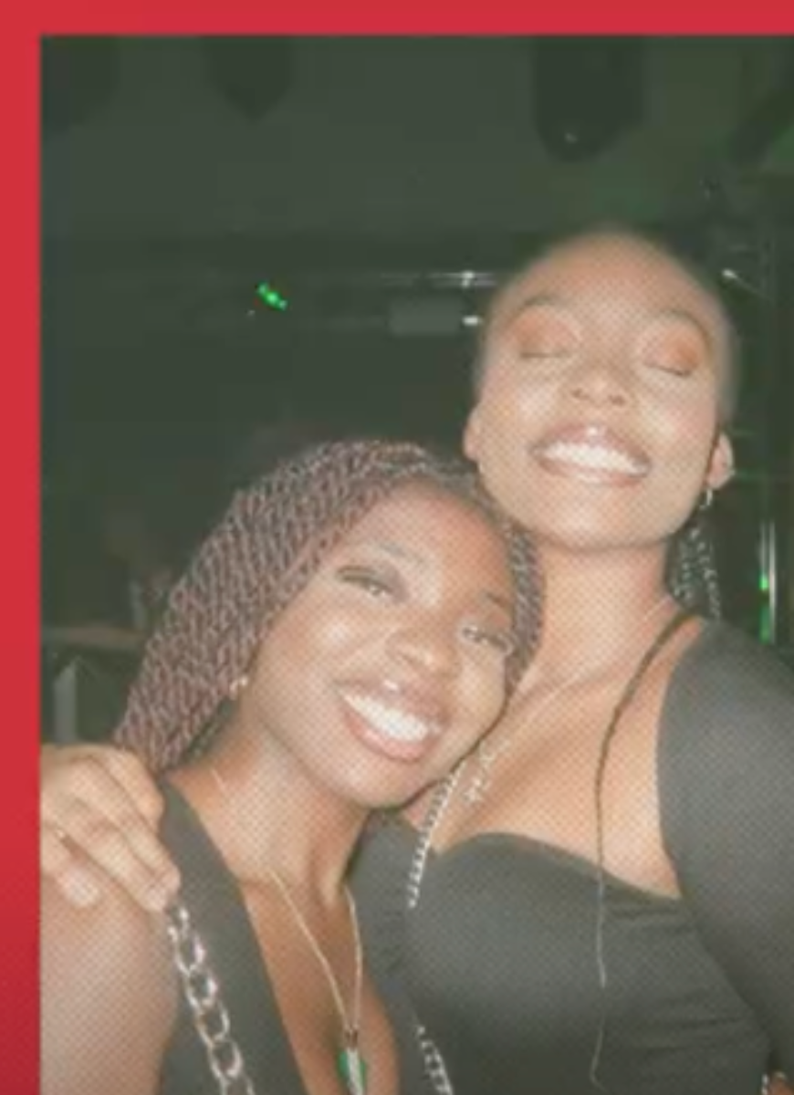 Two people smiling with a dark background behind them