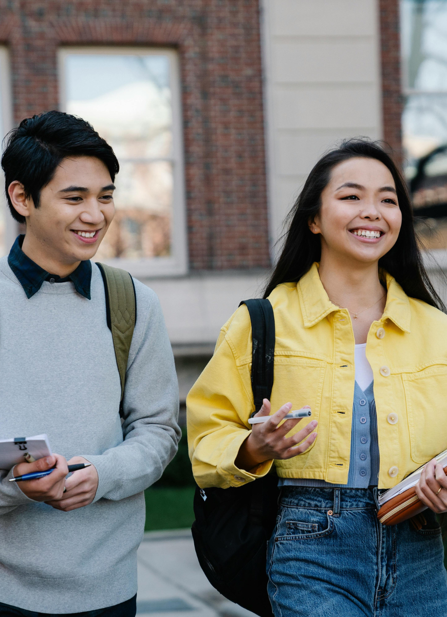 two students walking on campus holding books