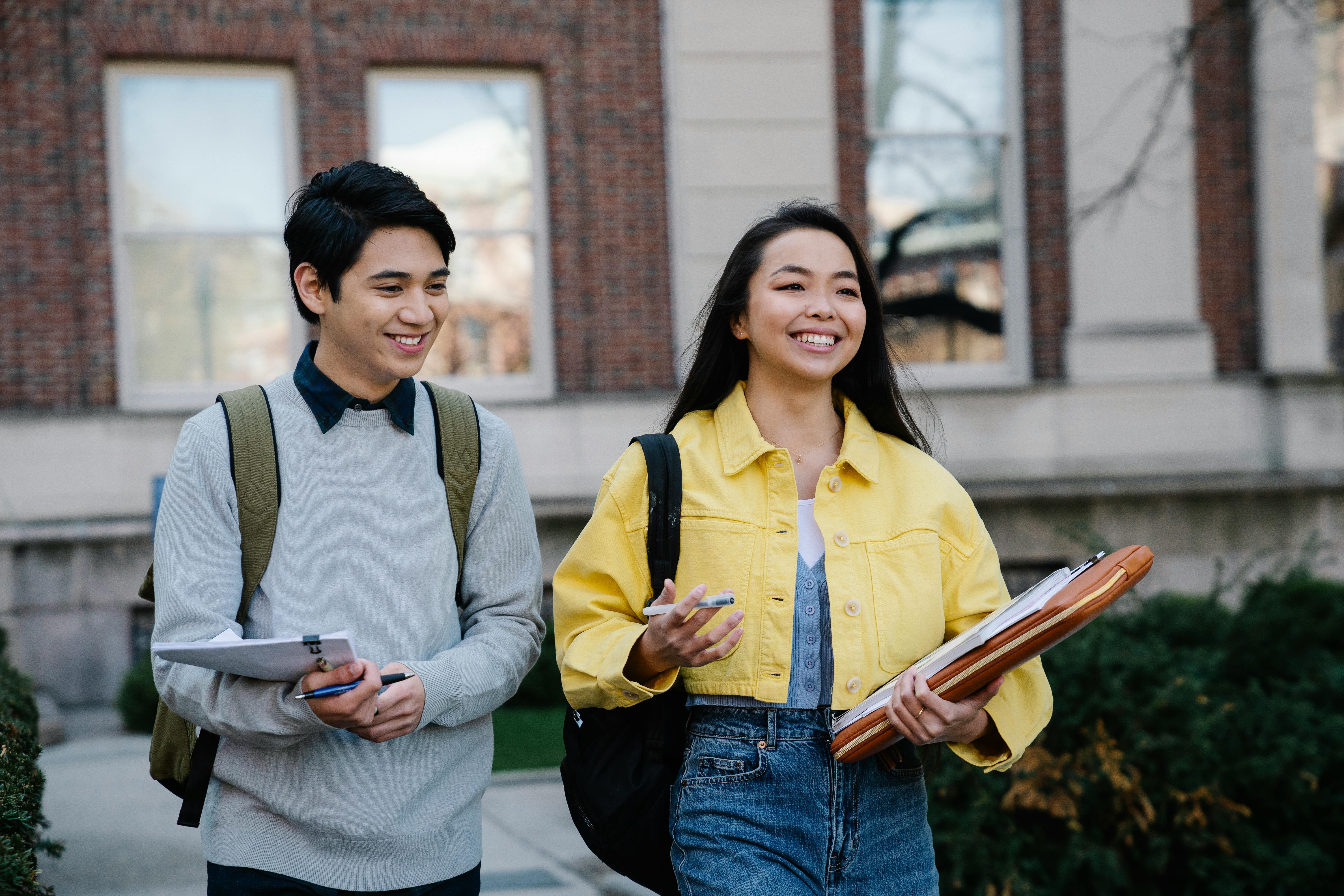 two students walking on campus holding books