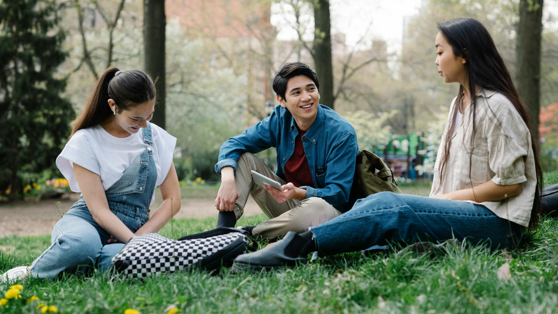 Three students sat on grass