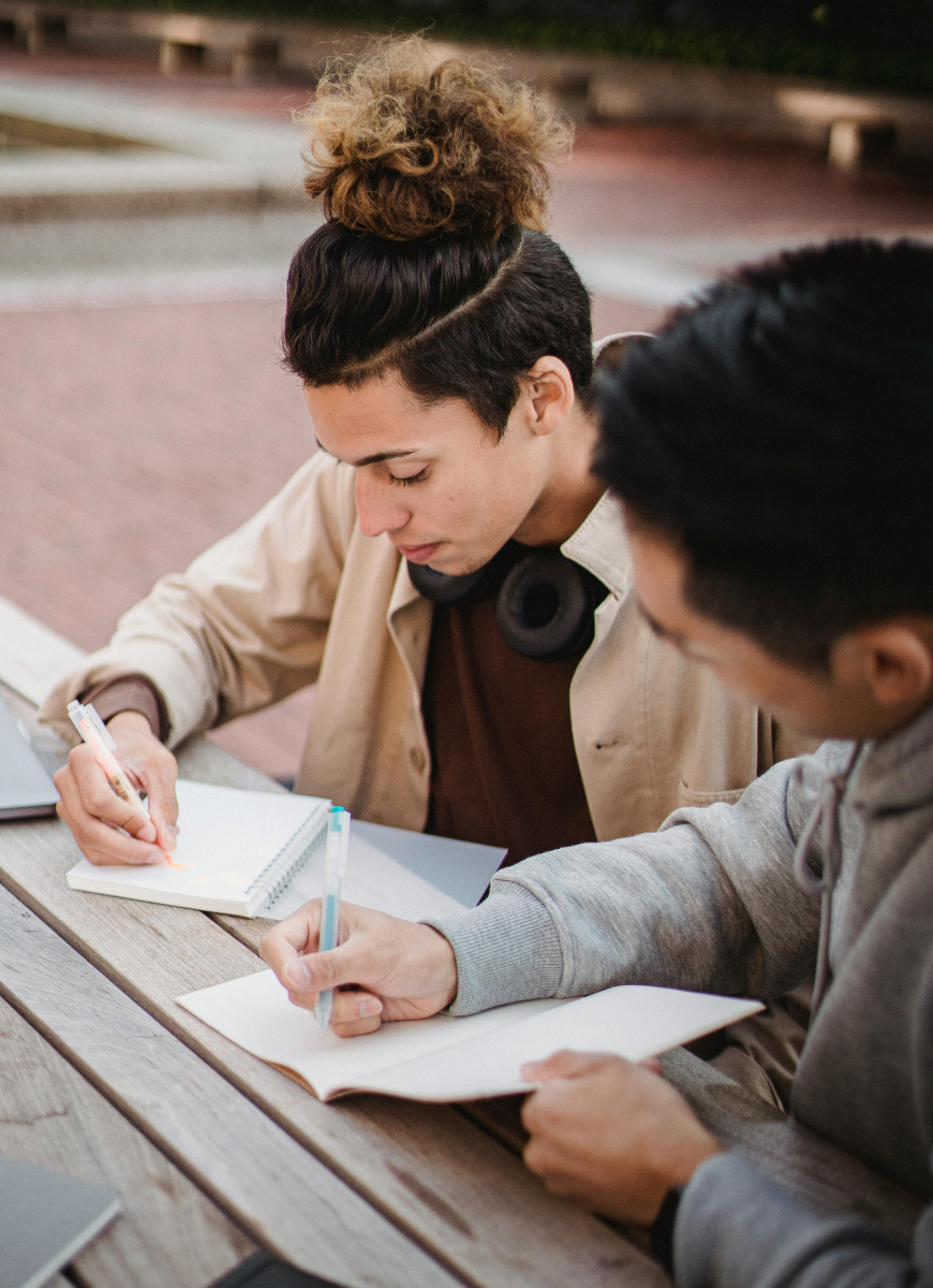 two male students sitting at a table writing