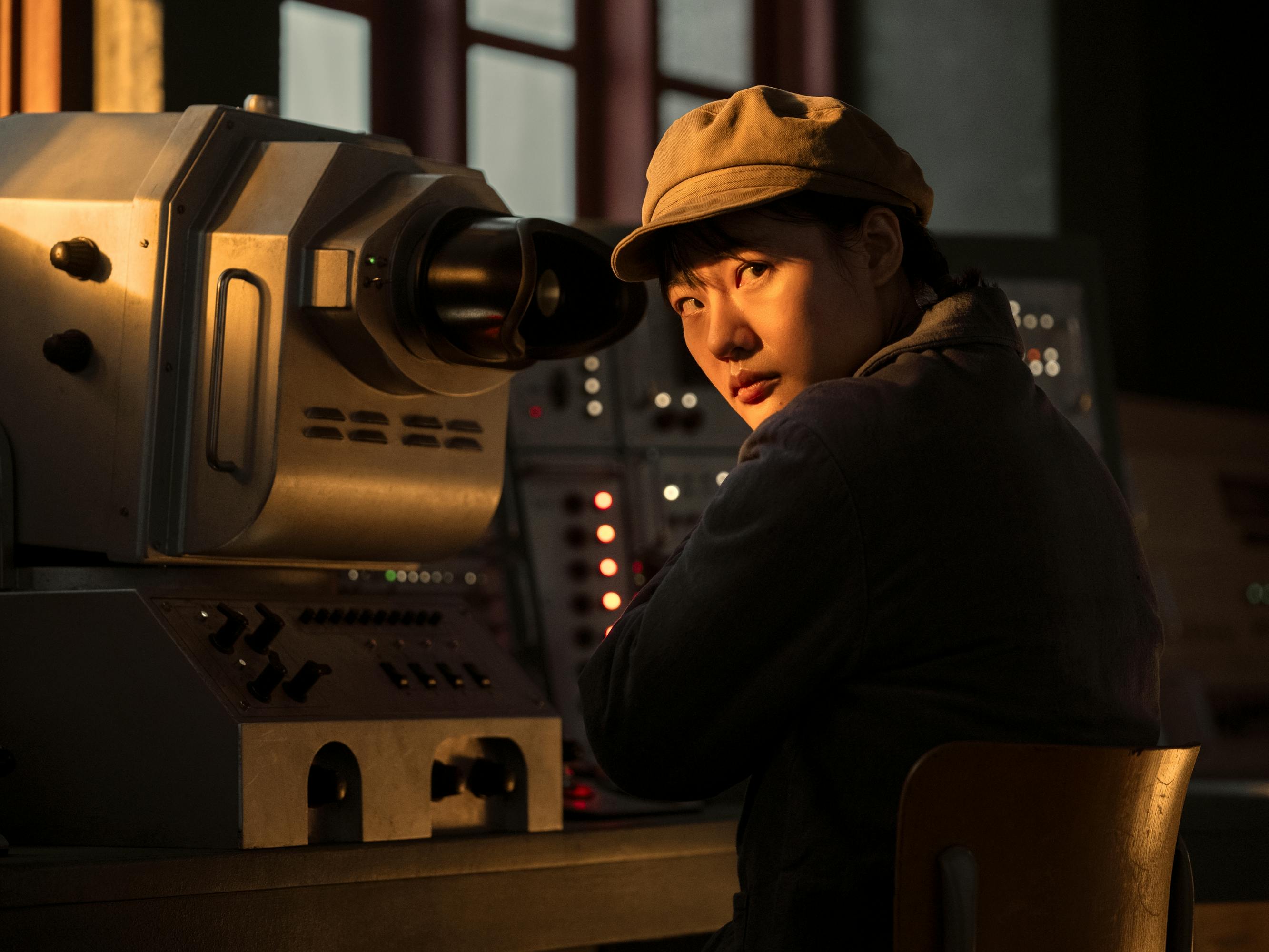 Young Ye Wenjie (Zine Tseng) looks through a telescope in golden light.