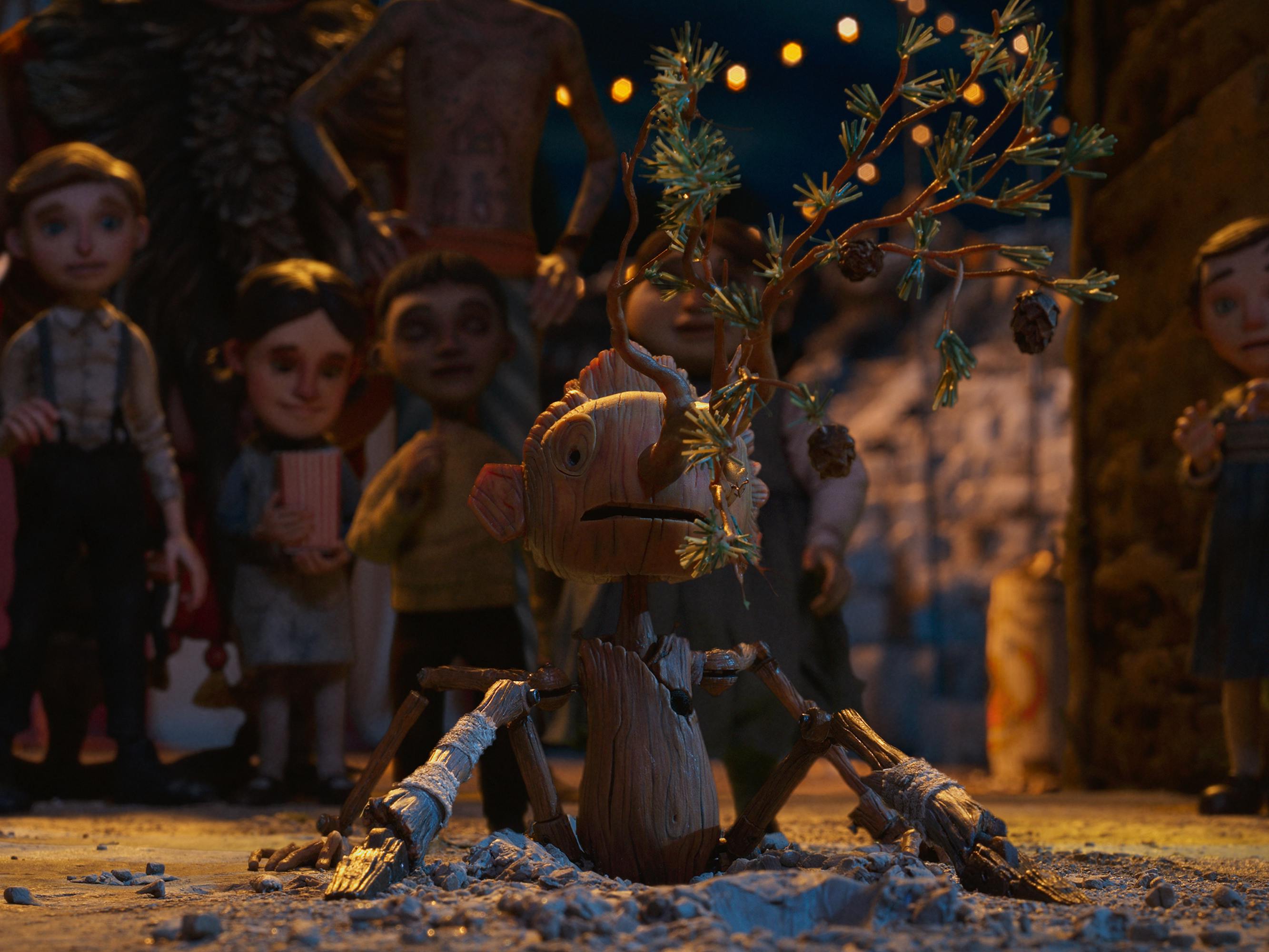 Pinocchio’s (Gregory Mann) nose grows into a small tree in front of a group of kids.