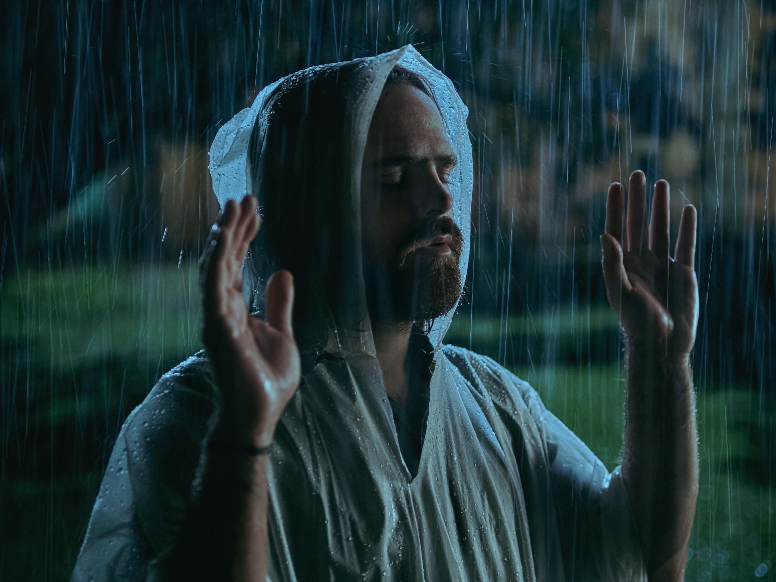 Tadeo (Peter Lanzani) wears a clear poncho and stands in the rain.