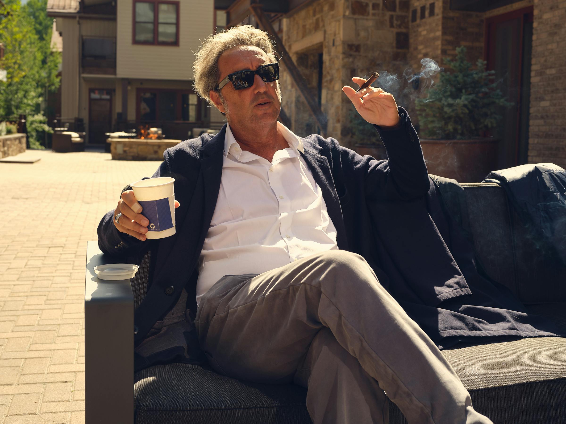 Paolo Sorrentino wears a white shirt, grey pants, and a navy cardigan.
