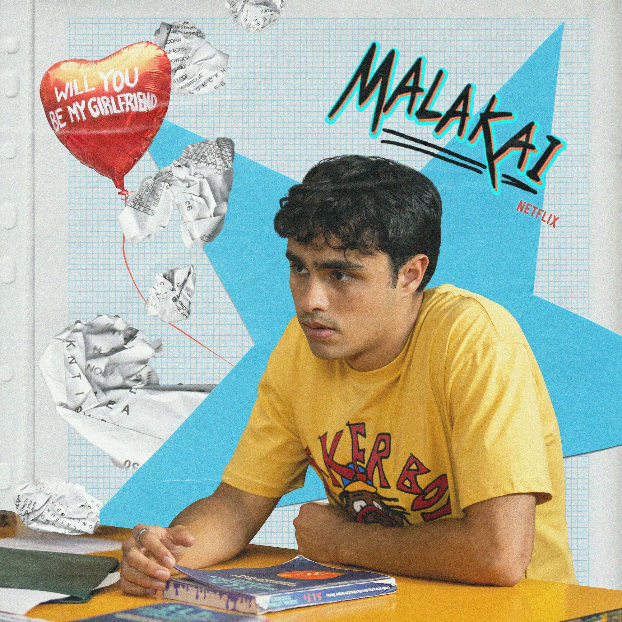 Thomas Weatherall plays Malakai and wears a yellow shirt sitting at a desk.