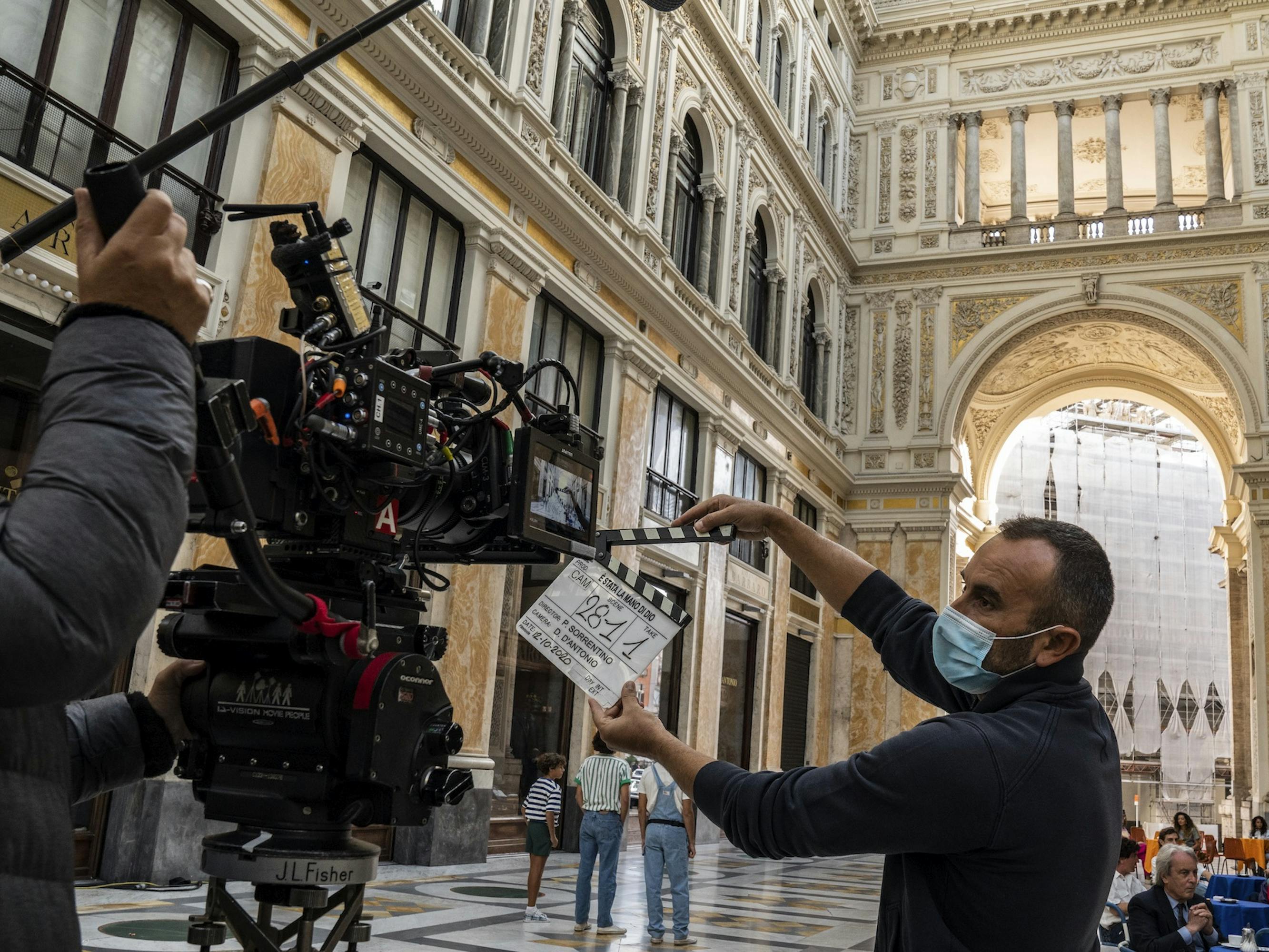 The Hand of God crew film a scene in an ornate, sunlit hall.