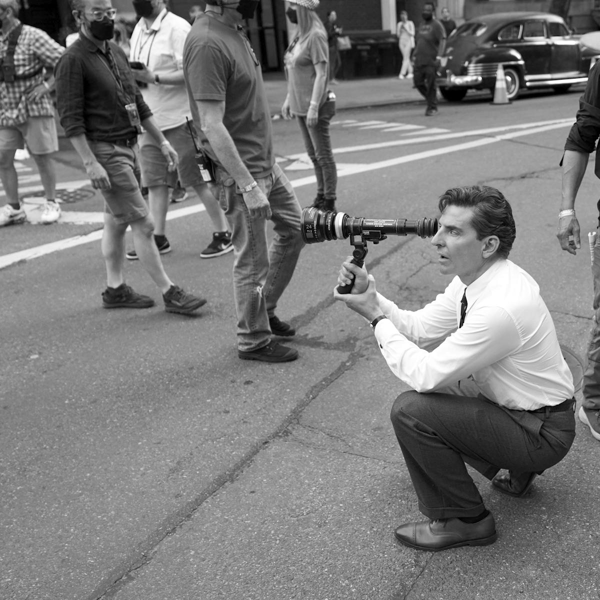 Bradley Cooper, behind the scenes of Maestro, looks through a camera.