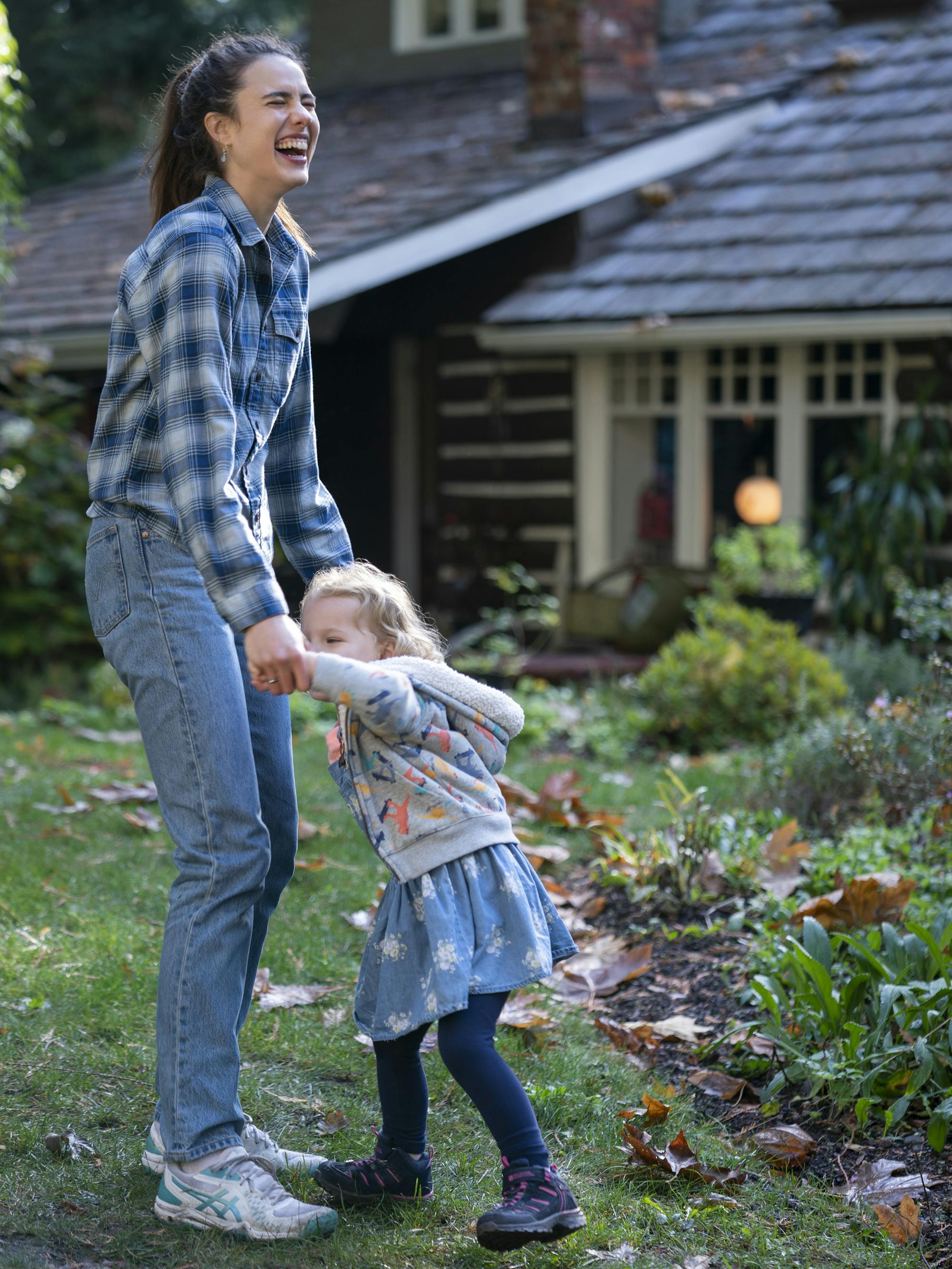 Alex Russell (Margaret Qualley) and Maddy Boyd (Rylea Nevaeh Whittet) giggle in the lawn outside a house.
