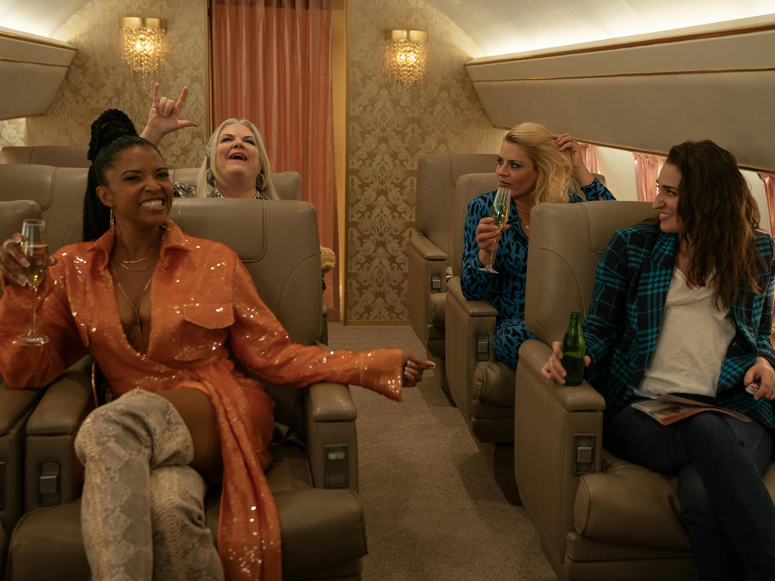 Wickie (Renée Elise Goldsberry), Gloria (Paula Pell), Summer (Busy Philipps), and Dawn (Sara Bareilles) sit on a private airplane.