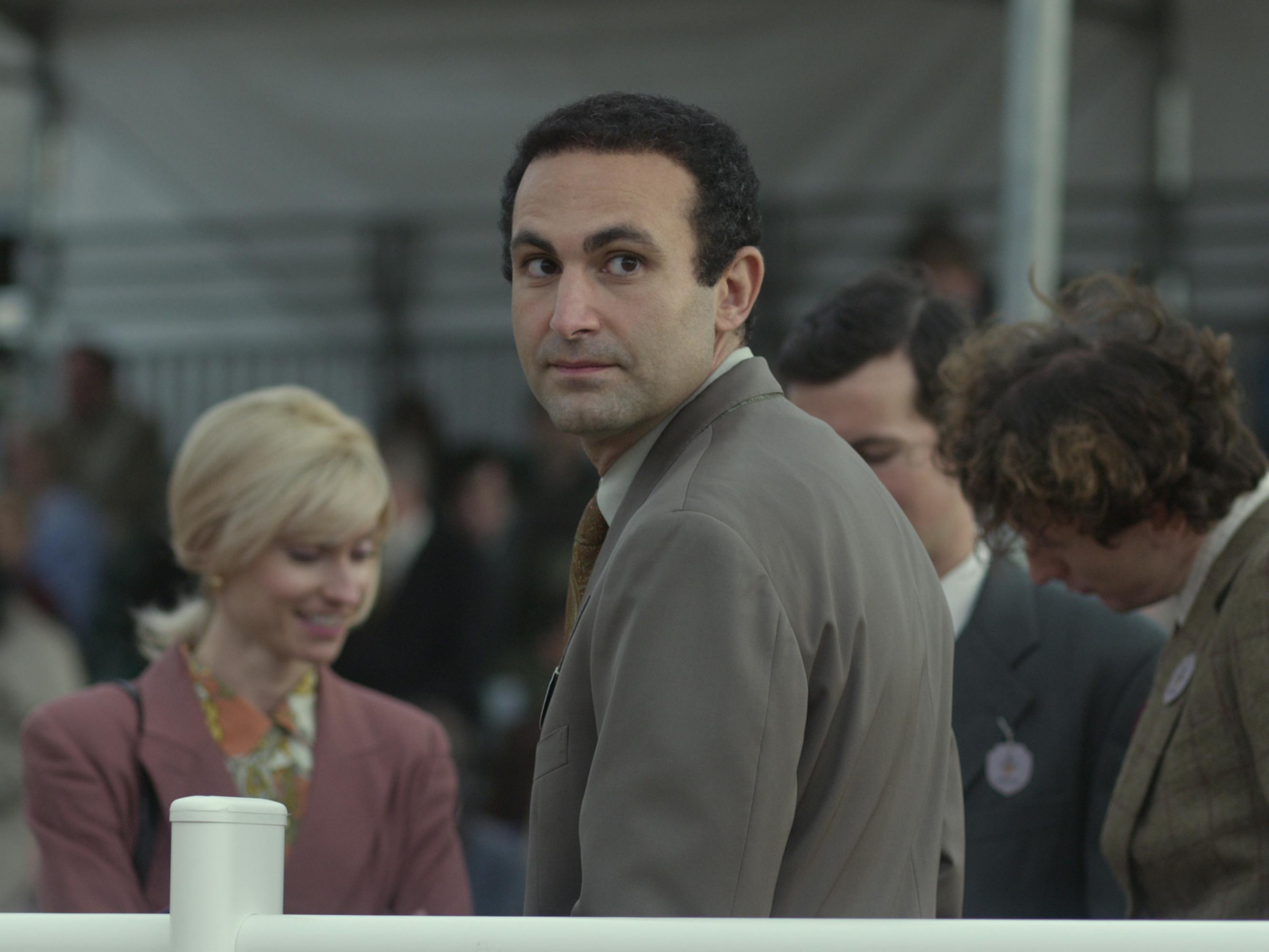 Dodi Fayed (Khalid Abdalla) wears a brown coat and looks behind his shoulder.