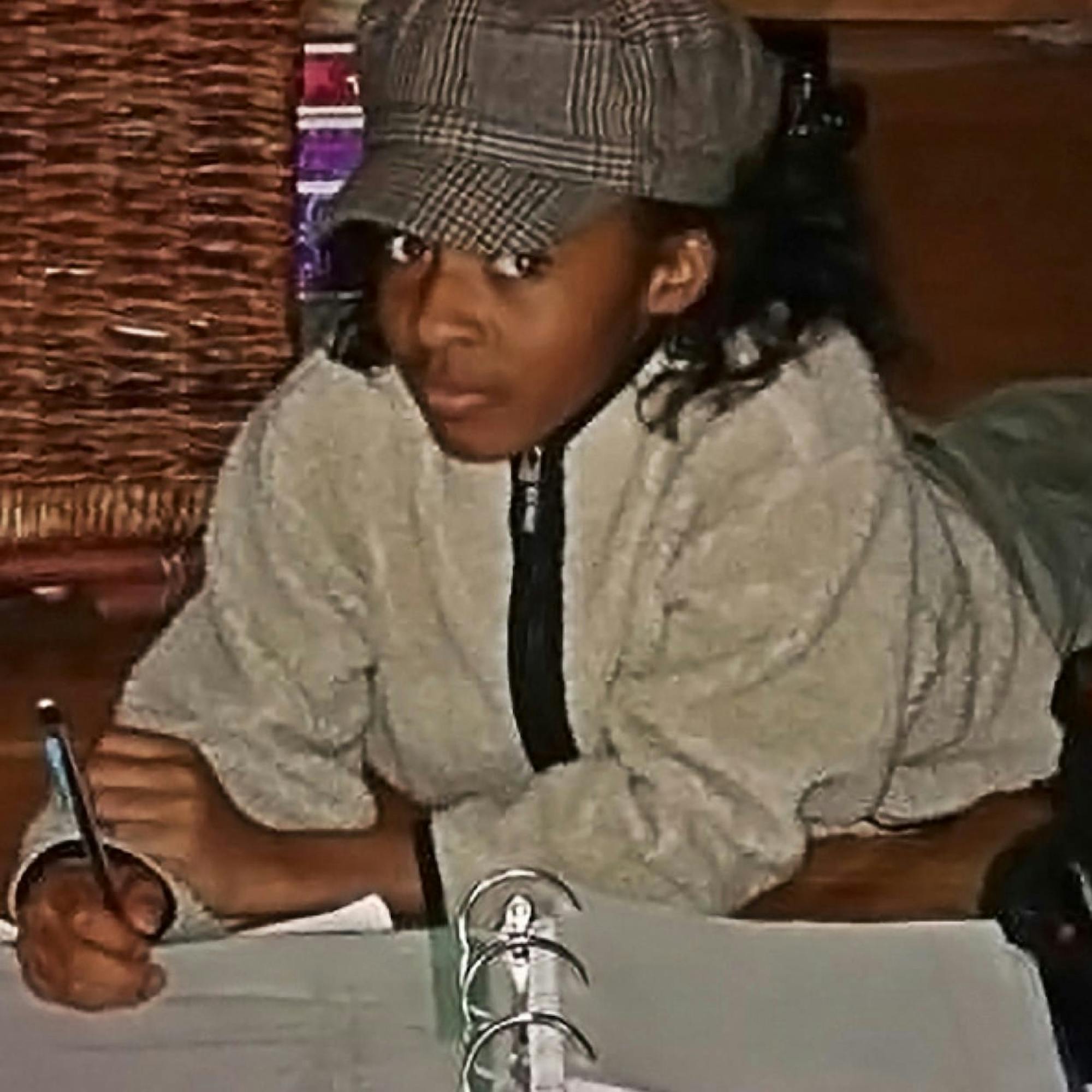 A throwback photo of Ayo Edebiri as a middle schooler, doing her homework in a large binder, looking oh so excited to be doing schoolwork.